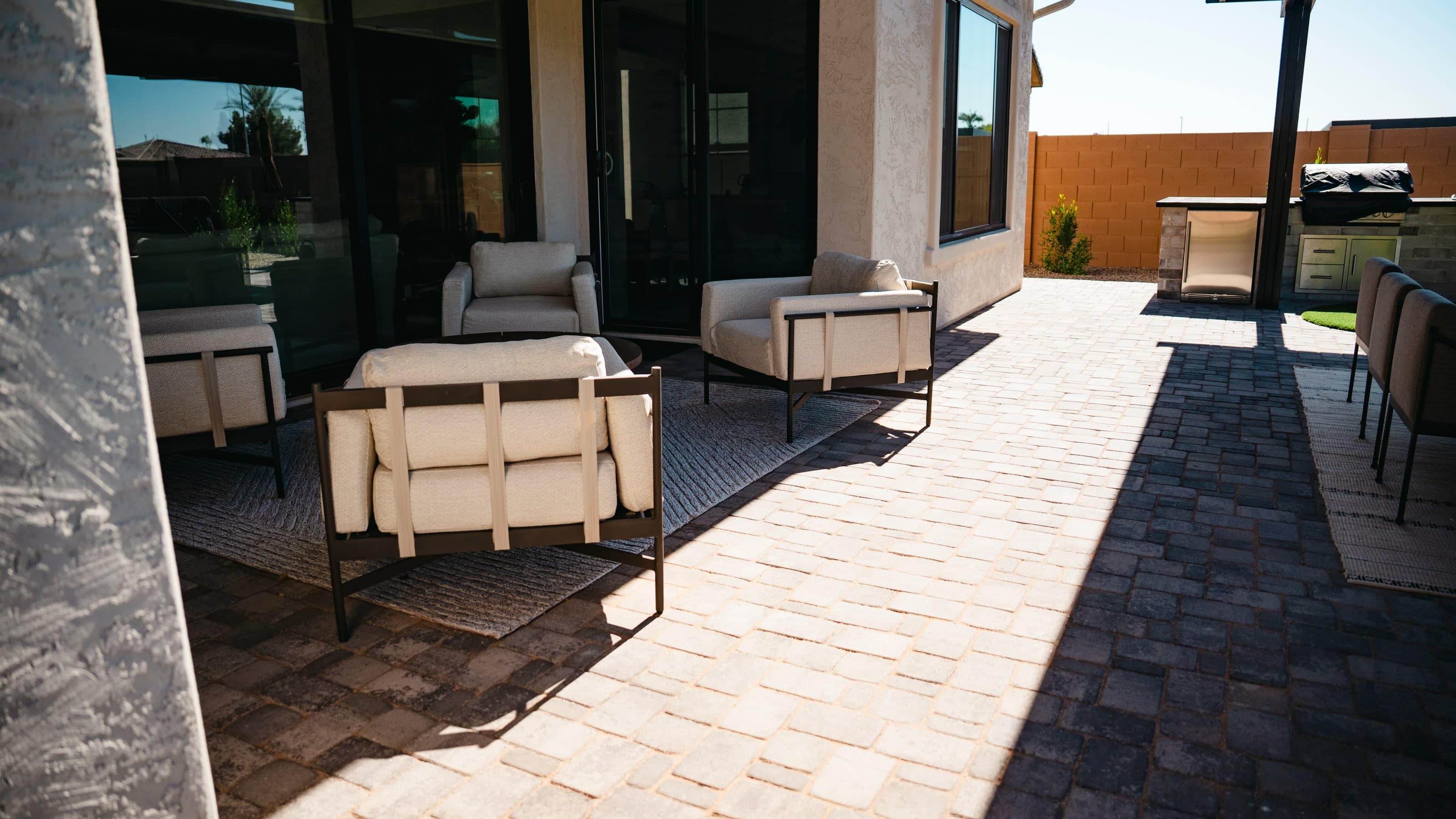 Covered patio lounge seating on a paver patio beside an outdoor kitchen counter