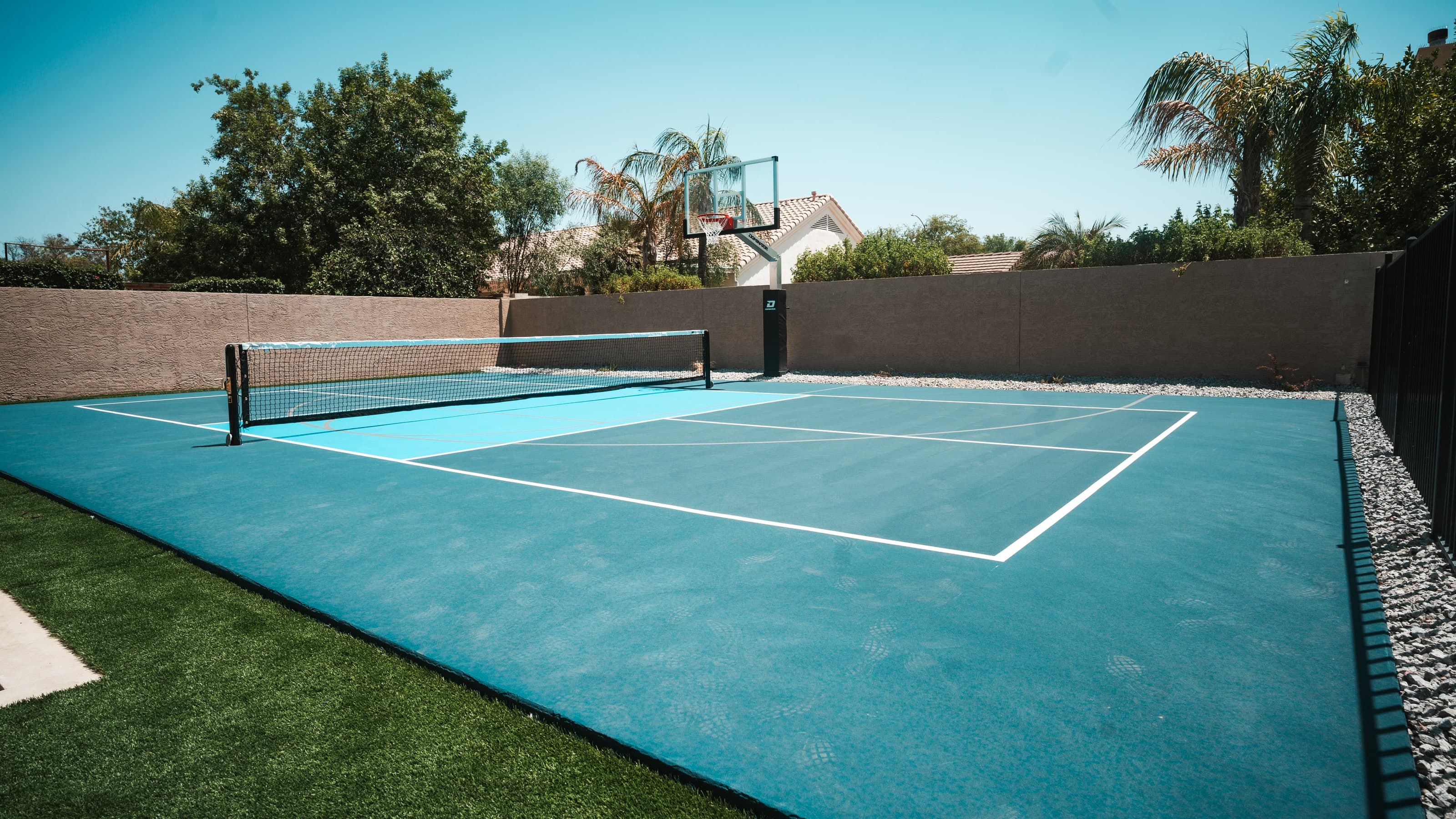 Backyard sport court with pickleball lines and a basketball hoop inside a block wall in Mesa