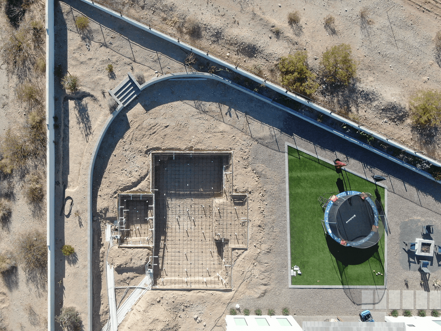 Overhead construction-progress photo of a Queen Creek backyard showing rebar and formwork for a pool and spa before concrete is poured