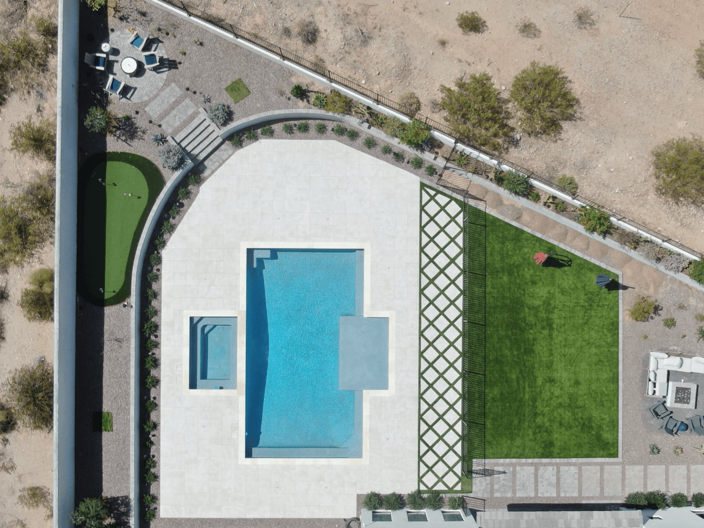Overhead photo of the completed backyard, showing a finished pool, spa, shade trellis, turf lawn, and putting green